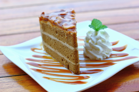 Piece of chocolate cake on a white plate on wooden