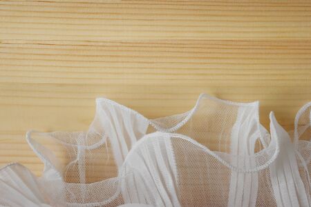 white fabric mesh has a soft ripple on natural wood table and empty space for text.