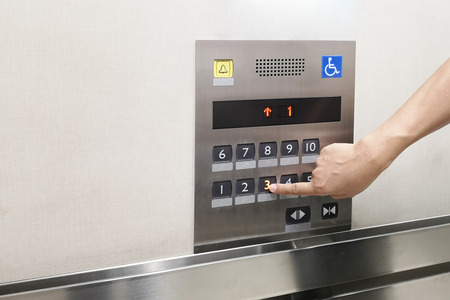 Men's hand with the press of control buttons interior elevator have braille panel for the disabled...
