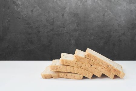 Whole wheat bread lay on a white background with a black wall.