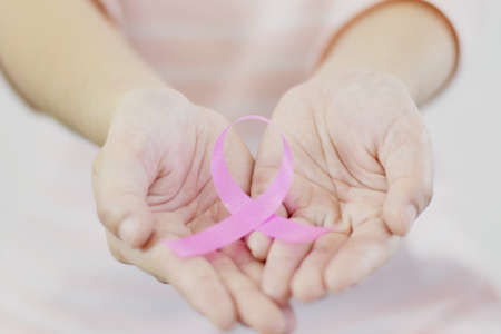 closed-up of woman with pink shirt is showing pink ribbon (Breast cancer symbol) on white isolated backgroundの写真素材