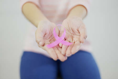woman with pink shirt is showing pink ribbon (Breast cancer symbol) on white isolated backgroundの写真素材
