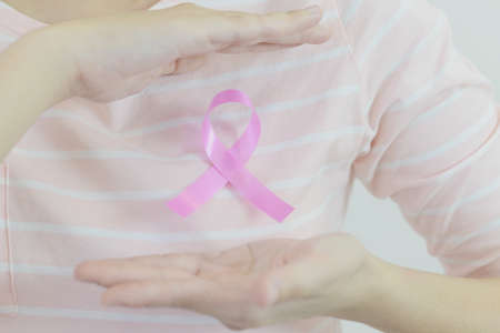 Woman with pink shirt is showing pink ribbon (Breast cancer symbol) on white isolatedの写真素材