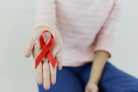 Asian woman with pink shirt is showing res ribbon (Aids symbol) on white isolatedの写真素材