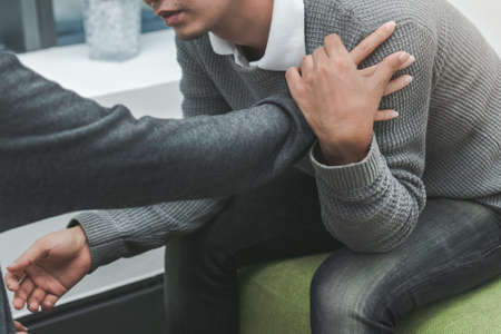 PTSD Mental health concept, Psychologist sitting and touch young depressed asian man for encouragement, Selective focus.の写真素材