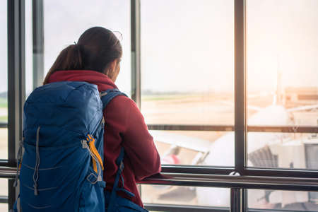 Traveler asian woman standing at the window in hall airplane departure with backpack , Selective focus, Travel concept.の写真素材