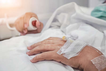 Close up on asian woman hand of a patient with push red button for emergency case in hospital ward, Selective focus, Healthcare concept.の写真素材