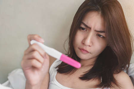 wellness and healthy concept, infertility problem,Unhappy young asian woman holding pregnancy test showing a negative result, Selective focus.の写真素材