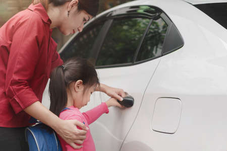Back to school concept, Beautiful young asian mother or parent helping daughter or pupil to getting in the white car to ride to school, Selective focus.の写真素材