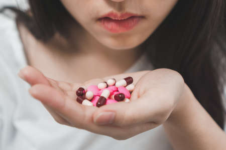 Suicide prevention concept, Close up hand of young asian woman taking medicine overdose trying to kill herself.Sick woman take a lot of pills.の写真素材