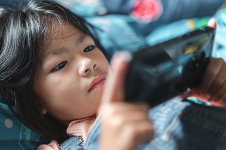 Little cute girl playing games on her smathphone on morning time after wake up, Selective focus, Childrenâs Smartphone Addiction problem.の写真素材
