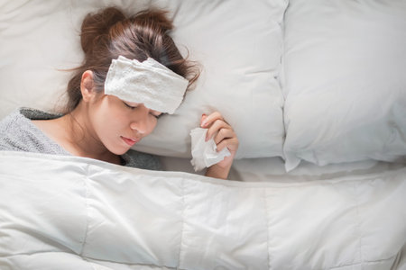 Sick asian woman have hight fever flu and sneezing into tissue on bed in bedroom, Medical and health concept, Selective focus.の写真素材