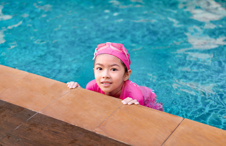 Young asian girl in swimsuit smilling in siwmming pool, active summer vacation concept.の写真素材