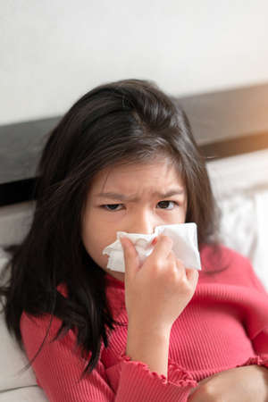 Sick asian girl have hight fever flu and sneezing into tissue on bed in bedroom, Healthcare and prevent the spread infection virus concept, Selective focus.の写真素材