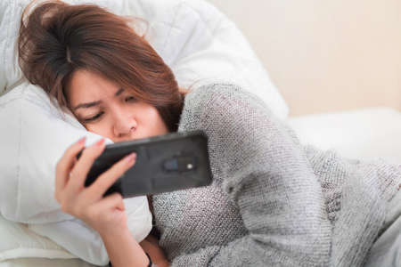 Sick asian woman have hight fever flu and checking temperature by digital thermometer on bed in bedroom, Medical and health concept, Selective focus.の写真素材