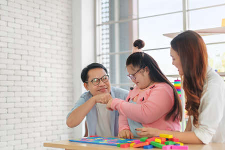 Happy asian father and mother playing education toy with their daughter down syndrome child in living room, Activity happy family lifestyle concept.の写真素材