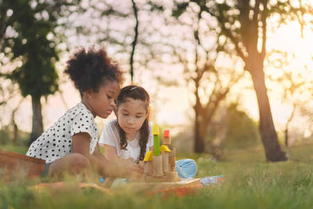 Happy cheerful ethnic girls  laying on mat at outdoors park, Her smiling and laughing together, Relationship little kids, Diverse ethnic concept.の写真素材
