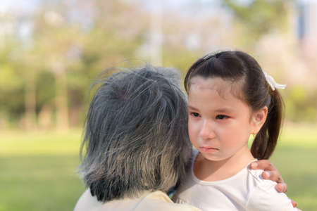 Asian mix girl crying, Parent or grandfather hugging baby for soothe, her have felling sad with tear ,Relationship family concept.の写真素材