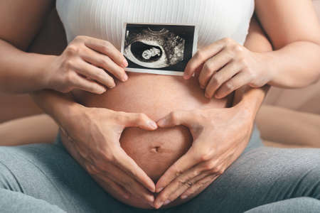 Young pregnant asian woman touching her belly, she holding baby in pregnant belly isolate on white...