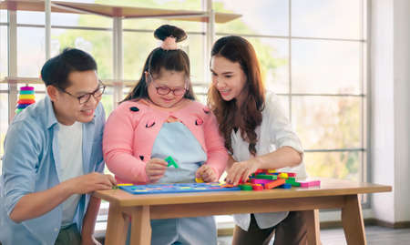 Happy asian father and mother playing education toy with their daughter down syndrome child in living room, Activity happy family lifestyle concept.の写真素材