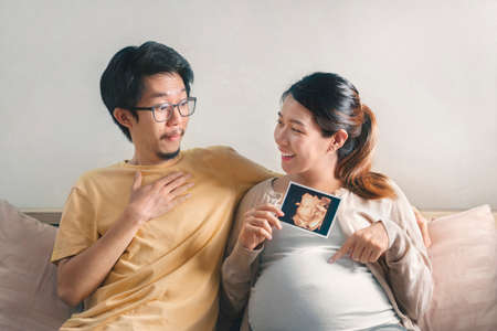 Young pregnant asian woman touching her belly, she holding baby in pregnant belly isolate on white background,  Maternity prenatal care and woman pregnancy concept.の写真素材