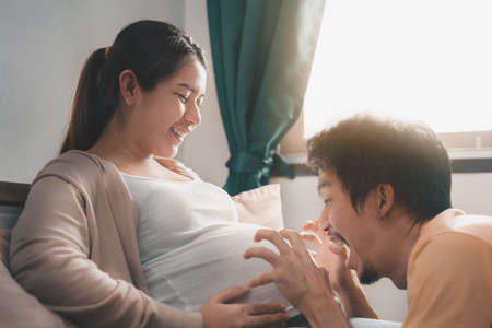 Young pregnant asian woman touching her belly, she holding baby in pregnant belly isolate on white background,  Maternity prenatal care and woman pregnancy concept.の写真素材