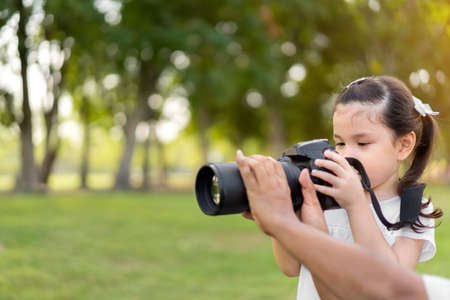 Asian caucasian mixed race girl learning to take a image from camera, Father taught her daughter, at outdoor park.の写真素材