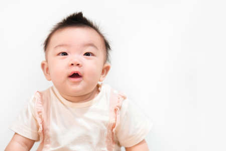 Asian babe girl 5 month with pink bow lying on stomach at bedroom.の写真素材