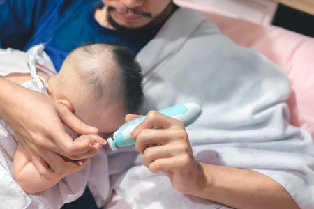 Father cutting my baby's nails with electic nail clipper while baby sleep.の写真素材