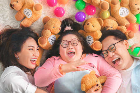 Happy asian family sitting on carpet and playing throw a lot of colored balls with their daughter down syndrome child, Activity happy family lifestyle concept.の写真素材