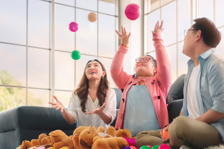 Happy asian family sitting on carpet and playing throw a lot of colored balls with their daughter down syndrome child, Activity happy family lifestyle concept.の写真素材