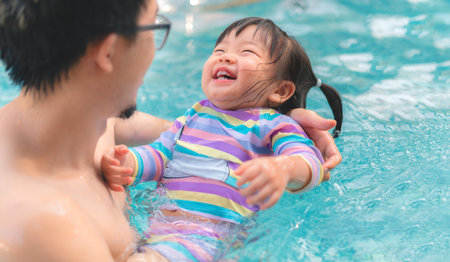 Asian little baby girl swimming in pool, Father holding daughter for safety support, Living...