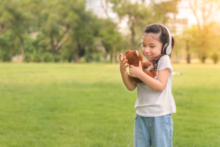 Caucasian mix girls play teddy bear doll at outdoors park, Picnic time.の写真素材