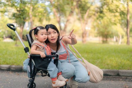 Asian mother walking with daugther in stroller in park,  Happy family concept.の写真素材