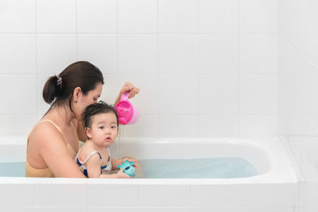 Asian mother and baby girl bathing together in bathtub, Happy lifestyle family concept.の写真素材
