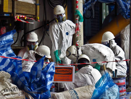 Songkhla province , Thailand: Feb 20, 2014: Man with protective mask and protective clothes in danger area. Worker wear chemical protective suit to change the filter at oil and gas plant. PPE suit.のeditorial素材