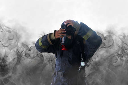 Firefighter in uniform in protective breathing mask on his head with inscription no problem on smoke background. Firefighter wear uniform and Full-face mask respirator.の写真素材