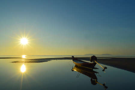Beautiful Sunrise at beach over a fishing boat in thailandの写真素材
