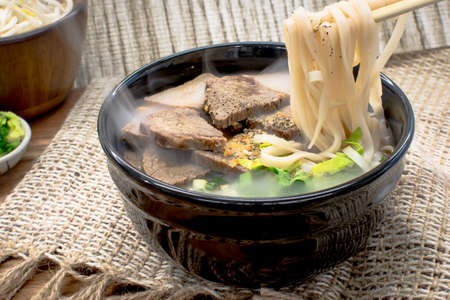 Beef noodle soup in black bowl
