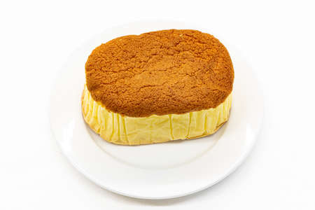 Sponge cake is on white plate and white background .Sponge cake is a light cake made with eggs, flour and sugar, sometimes leavened with baking powder.の写真素材