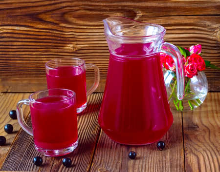 drink from blackcurrant in mugs and a jug on a brown wooden backgroundの写真素材