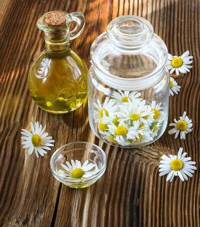 camomile flowers in a glass jar on a wooden backgroundの写真素材