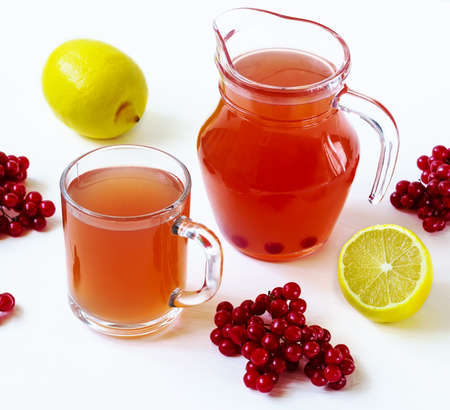 hot drink with a guelderrose and a lemon on a white backgroundの写真素材