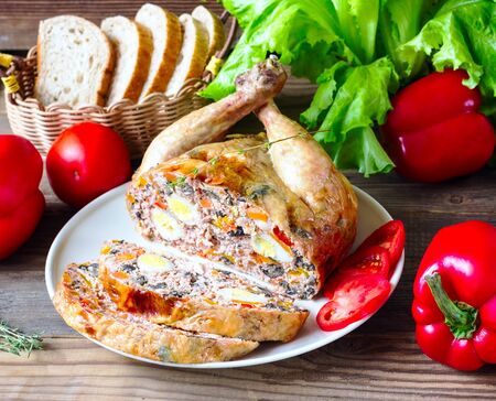 the chicken stuffed with vegetables and mushrooms on a brown wooden backgroundの写真素材