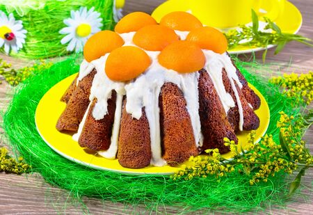 cake with glaze and apricots on a yellow plate with sisals and mimosas