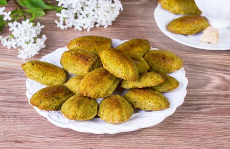 Madeleine on a white plate on a wooden background with white flowersの写真素材