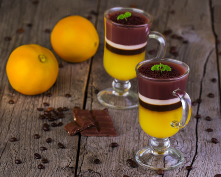 jelly with coffee, orange and chocolate in glasses on a wooden backgroundの写真素材