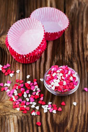 confectionery hearts and baking dishes on a wooden backgroundの写真素材