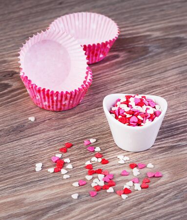 confectionery hearts and baking dishes on a wooden backgroundの写真素材