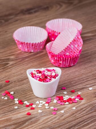confectionery hearts and baking dishes on a wooden backgroundの写真素材